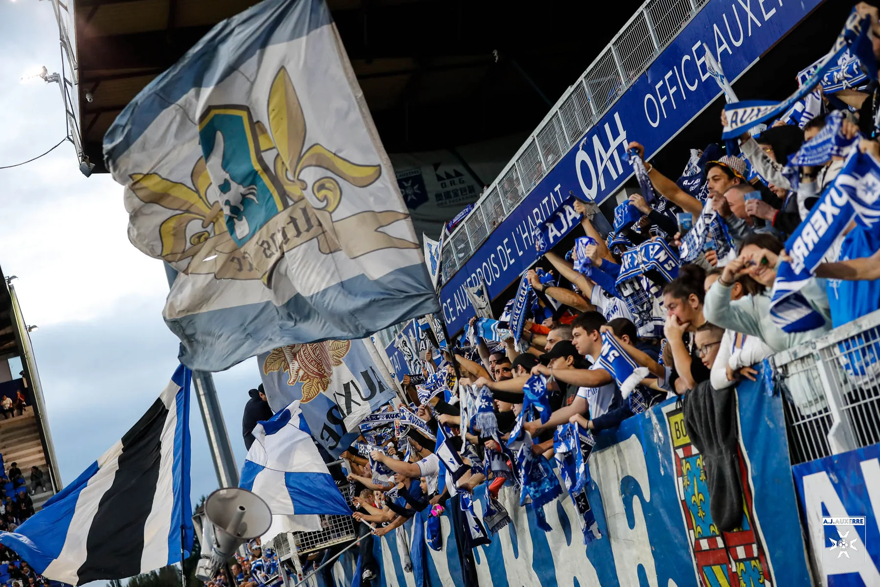 Auxerre supporters with blue and white scarves and flags at Stade Abbé-Deschamps